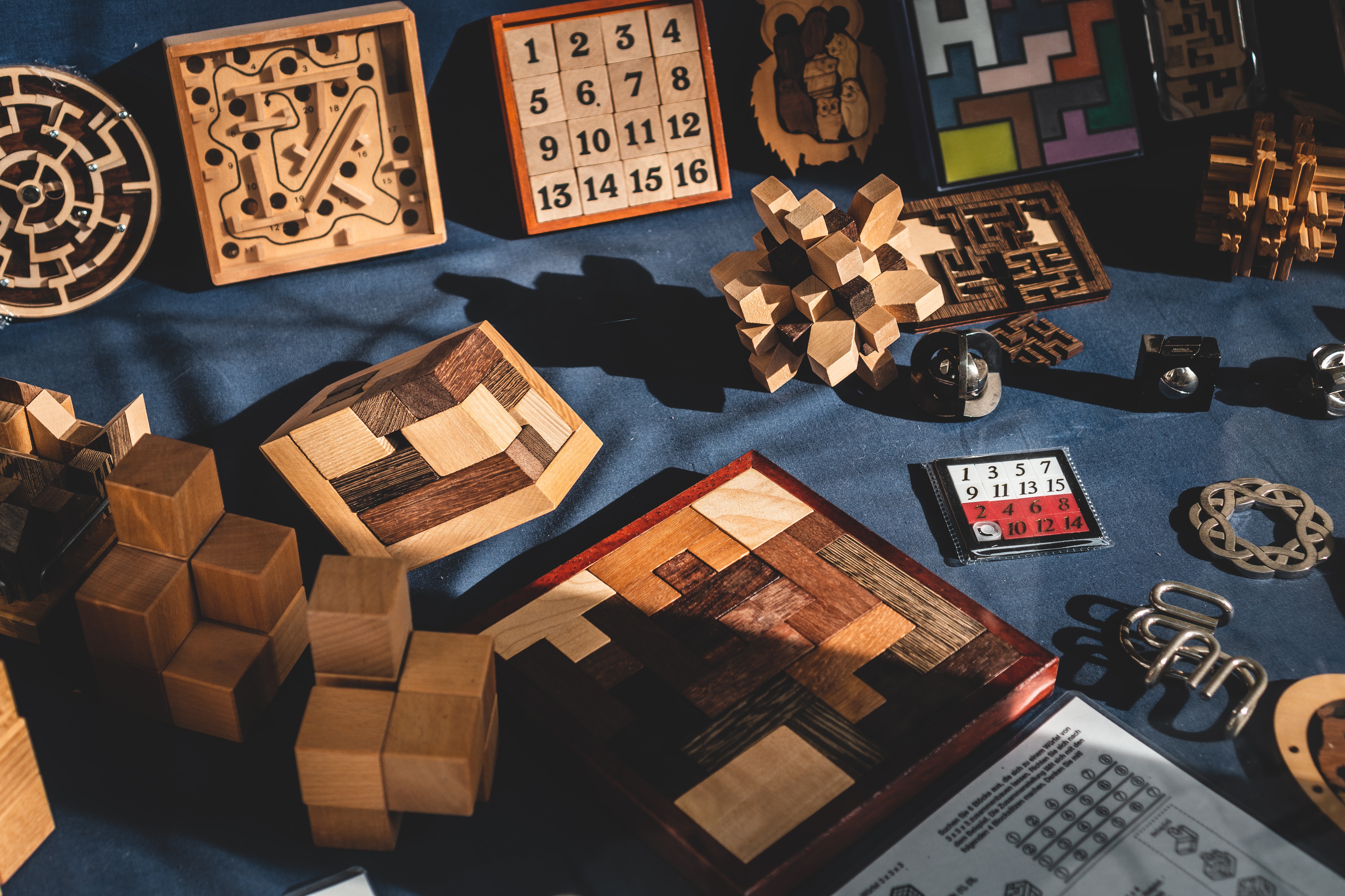 Several wooden puzzles and toys sitting on top of a piece of dark blue cloth.